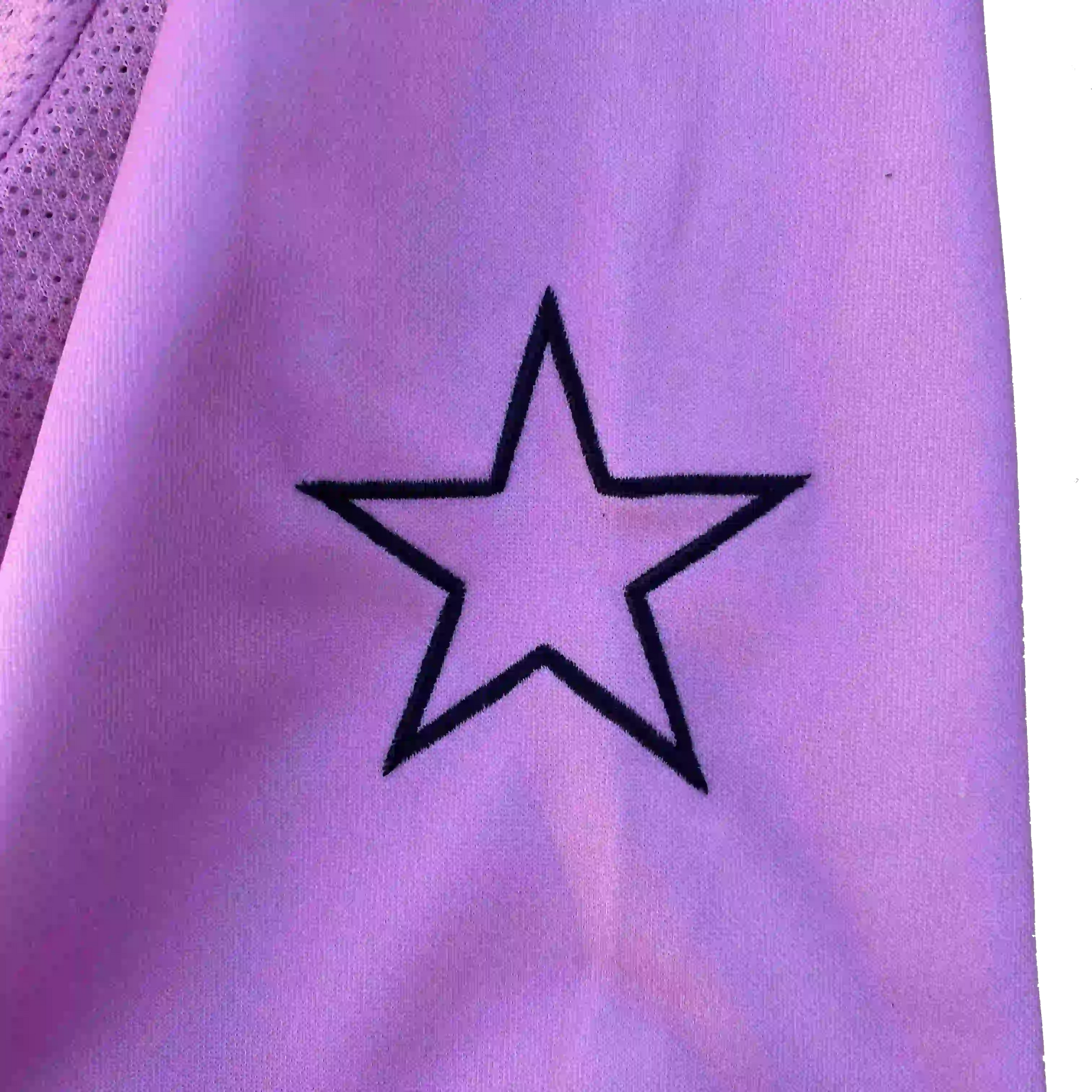 detail-etoile-noire-brodee-manche-maillot-rose-liberta-ozyx-texture-tissu-broderie-etoile