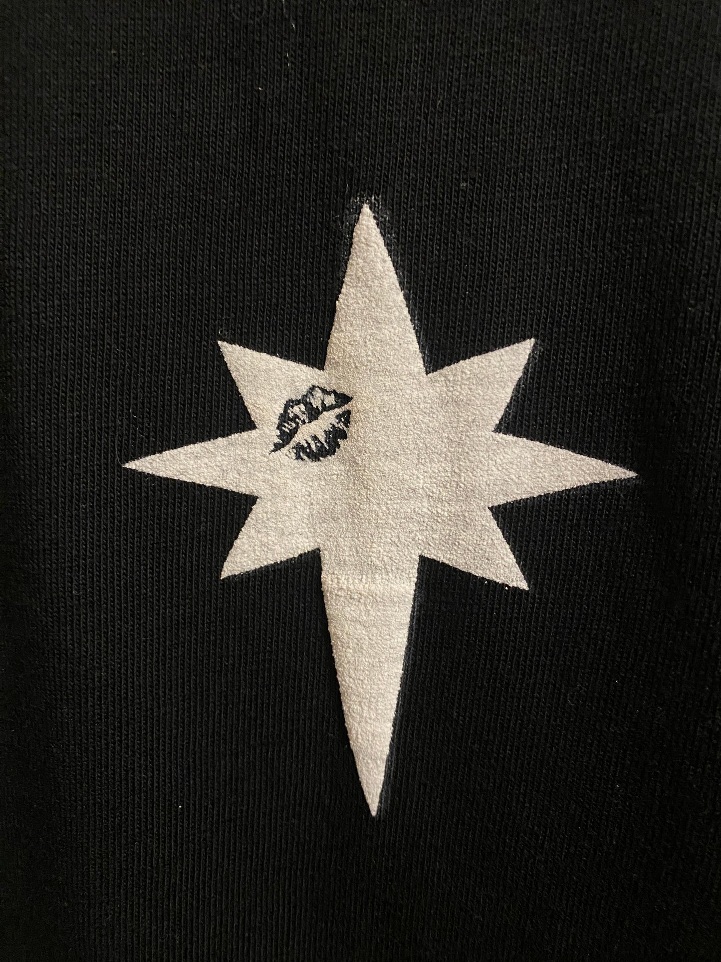 Zoom sur l'etoile à 8 branches avec un bisous sur un tshirt noir